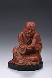 A CARVED SHOUSHAN SEATED 'TAMING LION' LUOHAN