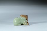A CELADON AND RUSSET JADE CARVING OF MYTHICAL BEAST