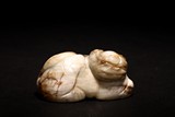 A CHINESE WHITE AND RUSSET JADE RECUMBENT LION
