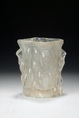 A CAST GLASS TREE TRUNK SHAPED BRUSH POT