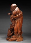 A WOOD CARVED BODHIDHARMA WITH LION STATUE