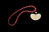 A STRAND OF CORAL BEAD NECKLACE WITH IVORY PENDANT