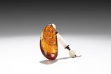 AN AMBER CARVED SHOULAO WITH WHITE JADE ORNAMENTS