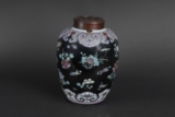 A BLACK GROUND FAMILLE ROSE JAR WITH COVER
