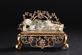 A CARVED CRYSTAL RECLINING BUDDHA ON GEM DECORATED GILT BRONZE STAND