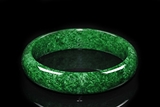 A MOTTLED DARK GREEN NATURAL JADEITE BANGLE