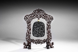 A BLACK JADE CARVED HANGING PLAQUE WITH CARVED WOODEN FRAME