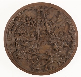 A CIRCULAR WOODEN CARVED BATTLE SCENE PLAQUE