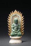 A SPINACH GREEN JADE BUDDHA WITH GILT-BRONZE MANDORLA
