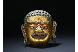 A GILT COPPER TIBETAN REPOUSSE DEITY MASK