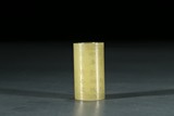 A SMALL YELLOW JADE INSCRIBED CYLINDER BEAD