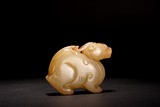 A WHITE AND RUSSET JADE CARVED MYTHICAL BEAST