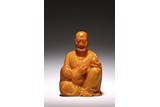 AN ORANGE SOAPSTONE CARVING OF LUOHAN