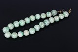 A CARVED CHINESE JADEITE BEAD NECKLACE