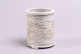 A RELIEF WHITE GLAZE 'BAMBOO AND FLOWERS' BRUSHPOT